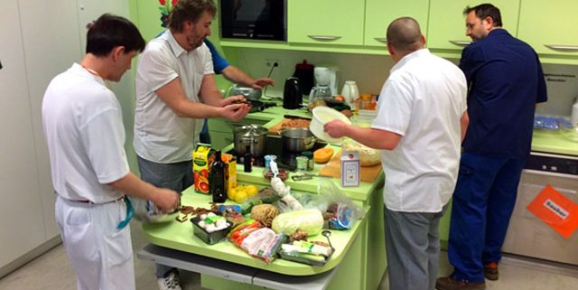 Fünf Männer bereiten in einer Küche Essen zu