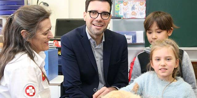 Stadtschulratpräsident Heinrich Himmer und zwei Kinder mit einer Mitarbeiterin des Samariterbundes mit Hund