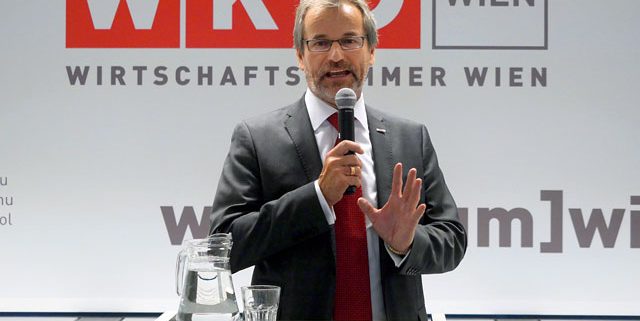 Ein Mann steht vor einem Podium und spricht in ein Mikro. Im Hintergrund das Logo der Wirtschaftskammer Wien