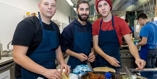 3 junge Männer kochen in einer Küche
