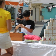Eine junge Frau von hinten steht vor einem Tisch mit verschiedenen Ausstellungstücken, unter anderem eine Ernährungspyramide aus Kartonwürfeln. Davor steht ein Junge, der sich mit den Materialien beschäftigt.